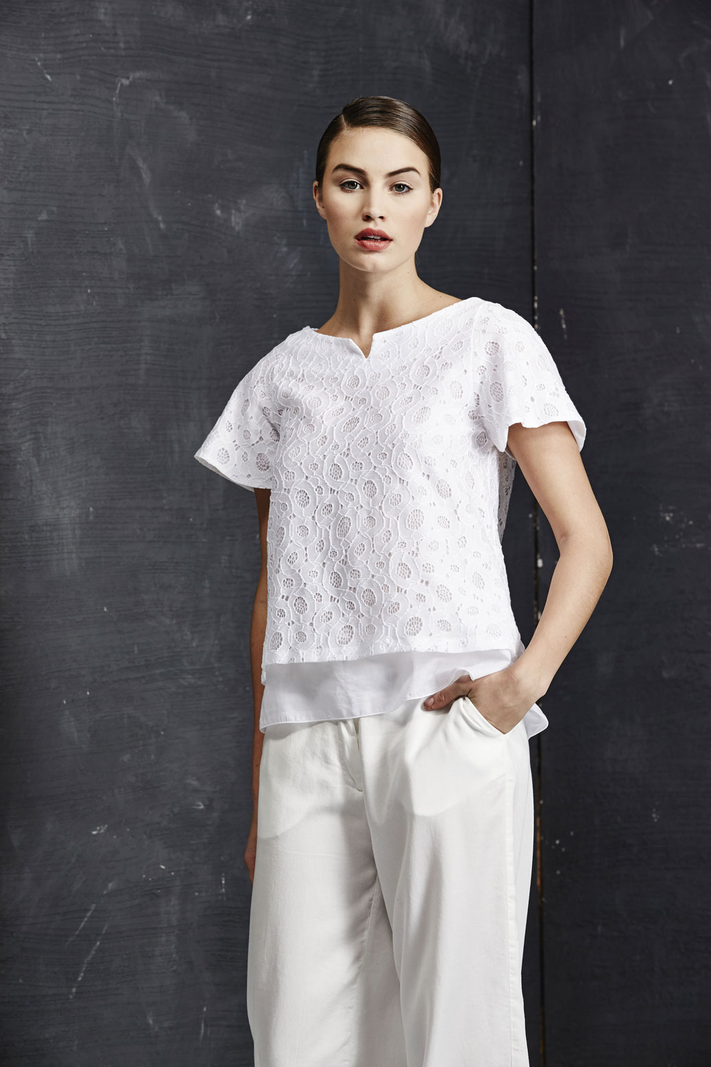 This model wears a blouse in cotton and macramè lace on a loose-fitting flowing trousers